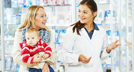 Pharmacist talking with a woman with a young baby in her arms