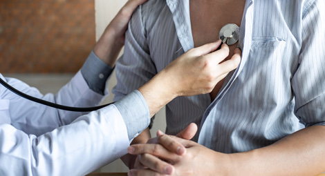 Clinician using stethoscope to list to male patients chest